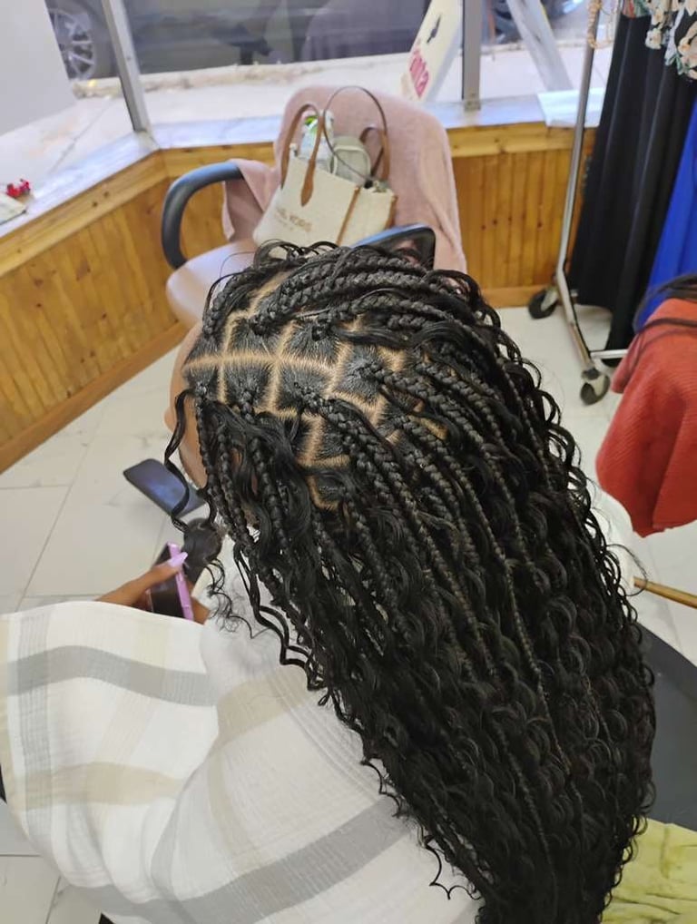 Back view of person with long black braided dreadlocks sitting in a salon chair