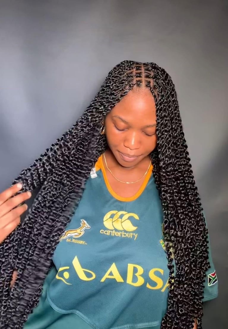 Woman with long black braided hair wearing a teal Canterbury rugby jersey with ABAB logo, looking downward against gray background