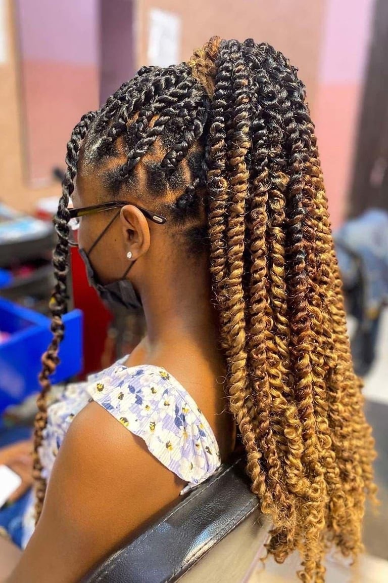 Side profile of a person wearing glasses with long braided hair in golden-brown tones and cornrow details